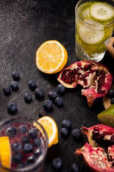 Lemons, pomegranate and berries on dark wooden background in studio photo