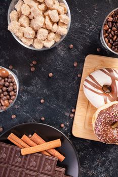 Candies, brown sugar, donuts and coffee on dark vintage wooden background