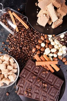 Top view of brown sugar, chocolate tablets and cinnamon sticks on a wooden background