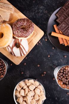 Different types of deserts on a black wooden table in studio photo