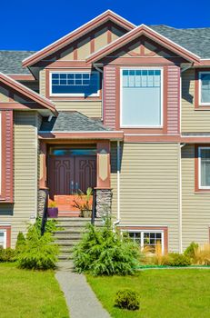 A perfect neighborhood. Main entrance of big family house with concrete door steps in front. Residential house with the entrance under the porch