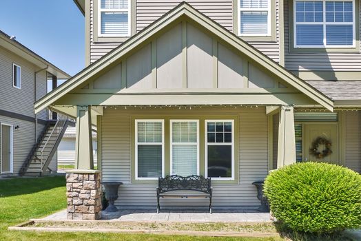 Facade of family house with casted bench at the window beside the entrance.