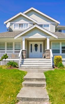 Entrance of family house with concrete pathway over green lawn in front.