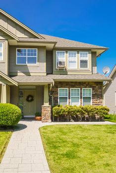 A perfect neighborhood. Entrance of family house with concrete pathway over green lawn to the front door