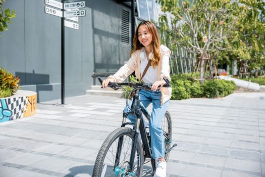 Happy Asian young woman riding bicycle on street outdoor near building city, Portrait of smiling female lifestyle use mountain bike in summer travel means of transportation, ECO friendly, Urban biking