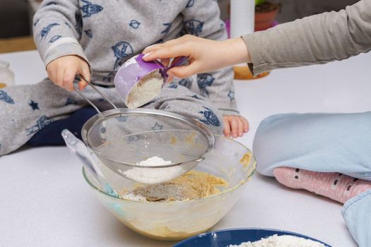 glass jar with brown sugar and a spoon in the background the hands of a woman preparing a cake