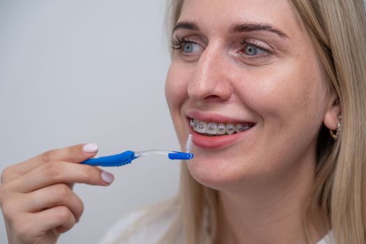 Caucasian woman cleaning her teeth with braces using a brush