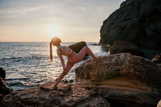 Young woman with black hair, fitness instructor in pink sports leggings and tops, doing pilates on yoga mat with magic pilates ring by the sea on the beach. Female fitness daily yoga concept