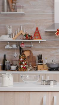 Empty xmas decorated culinary kitchen with nobody in it is ready for traditional christmas celebration. On table standing traditional homemade cookie dessert ingredients with milk glass