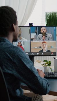 African american man waving to colleagues, talking on online conference internet call using webcam communication. Remote worker working from home keeping distance while using technology