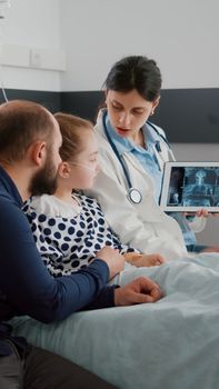 Physician woman doctor explaining medical radiography discussing healthcare treatment monitoring symptoms during recovery examination in hospital ward. Hospitalized child having breathing illness