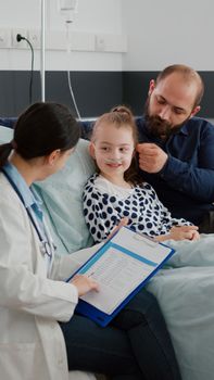 Physician woman doctor monitoring disease symptoms writing antibiotics treatment during recovery consultation in hospital ward. Hospitalized child with nasal tube recovering after breathing surgery