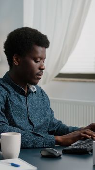 Confident remote african american black man worker doing his job from home, taking a sip of coffee, working from home. African ethnicity computer user in modern flat. Internet online browsing and communication