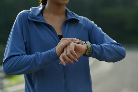 Cropped image of sports woman checking heart rate data on smartwatch. Healthy lifestyle, workout and wellness concept.