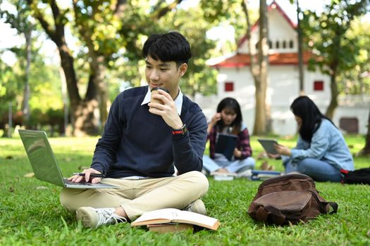 Smart asian students woman using laptop while sitting on campus lawn. Education and lifestyle concept.