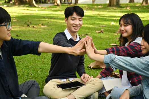 Shot of university students giving high five, celebrating together. University, youth lifestyle and friendship concept.