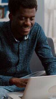 Authentic smiling black african american guy working from home, remote worker computer laptop user. Black freelancer using internet web online communication in modern flat