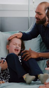 Medcial team trying to stop upset little child while monitoring heartbeat pulse examining disease symptoms during medicine consultation. Kid suffering panic attack in hospital ward