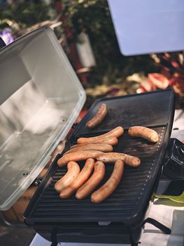 Fresh sausage and hot dogs grilling outdoors on a gas barbecue grill. Concept  picnic