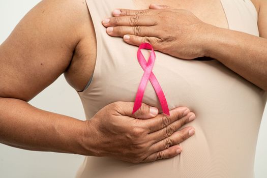 Breast cancer, pink ribbon at Asian senior lady for supporting awareness, symbol of World Breast Cancer Day.