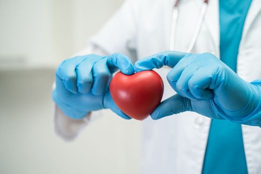 Doctor holding a red heart in hospital ward, healthy strong medical concept.