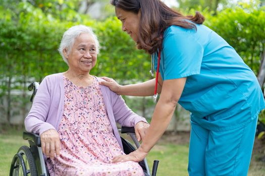 Doctor caregiver help and care Asian senior or elderly old lady woman patient sitting on wheelchair in park at nursing hospital, healthy strong medical concept