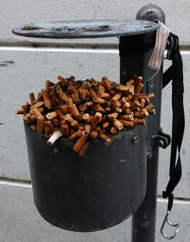 A place outside where smoking is allowed. By the heap of cigarette butts in the ashtray you can see that this is used a lot