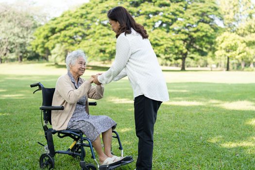 Caregiver help and care Asian senior or elderly old lady woman patient sitting on wheelchair in park, healthy strong medical concept.