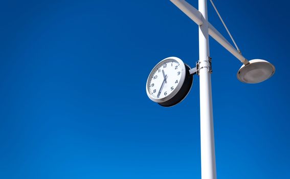 Outdoor clock construction on blue sky background in sunny day. Concept of time spending, work and rest