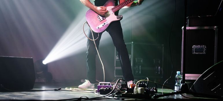 Rock guitarist on a stage playing music with spotlight on a background