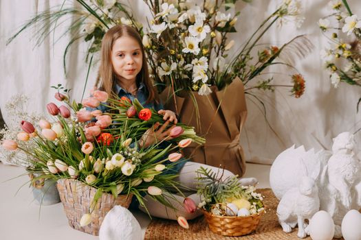 Two girls in a beautiful Easter photo zone with flowers, eggs, chickens and Easter bunnies. Happy Easter holiday