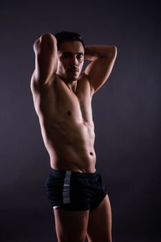 Handsome muscular shirtless young man standing confident, front view, looking at the camera