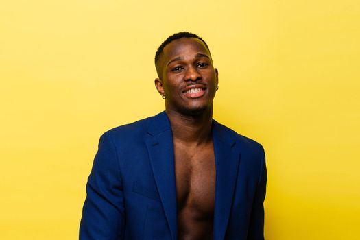 Guy in blue suit on a yellow background. Handsome athletic man in jacket smiling