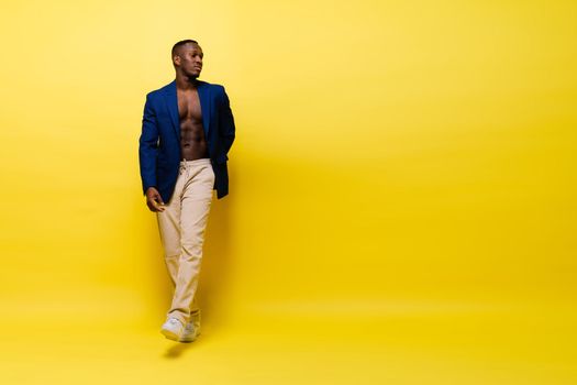 Guy in blue suit on a yellow background. Handsome athletic man in jacket smiling