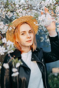 Portrait of a woman in a straw hat in a cherry blossom. Free outdoor recreation, spring blooming garden.
