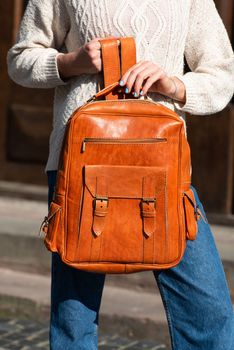 Woman with a orange leather backpack with antique and retro look. Outdoors photo.