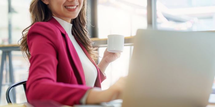 Smiling asian business woman with laptop computer in office. Woman in suit at office.