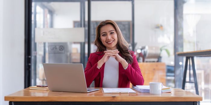 Portrait of Smiling asian business woman with laptop computer in office. Woman in suit at office.