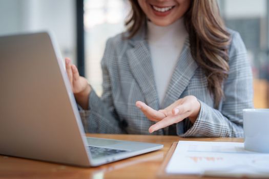 Smiling asian business woman with laptop computer in office. Woman in suit at office.