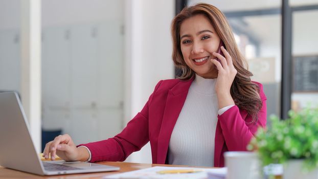 Portrait of Smiling asian business woman with laptop computer in office. Woman in suit at office.