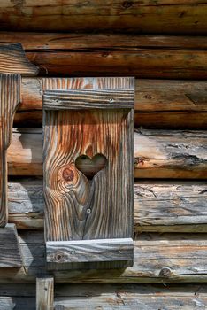 A window shutter decorated with a heart at a small wooden alpine hut.