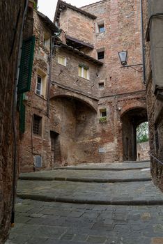 An alley with old buildings without people in the old town of the Italian city of Siena.