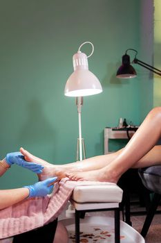 detail of a woman's legs receiving a moisturizing foot and leg massage after her pedicure treatment in the beauty salon, wellness and body care concept