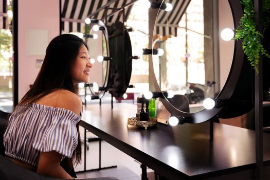 smiling young woman admires happy her new haircut and hairstyle in the hairdresser's salon mirror, beauty care and wellness concept