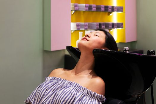 young woman waiting in the hairdressing area of a beauty salon to have her hair washed, concept of wellness and hair care