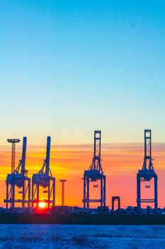 Shipyard cranes shipyard crane and container port with cold and snow in winter at sunset in Weddewarden Bremerhaven Germany.