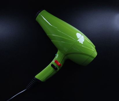 Bright green background on black background. Reliable hair dryer for home use concept