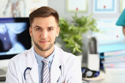 Portrait of young handsome male doctor in clinic. Medical services and insurance concept