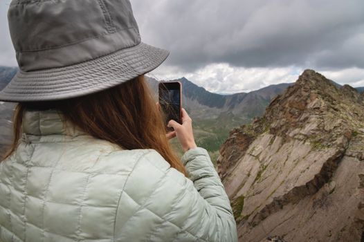 a woman in panama stands with her back to the camera and photographs the mountains on the phone, a tourist takes a selfie on a hike.