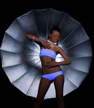 Sexy Girl dance with ultraviolet glow make-up and silver umbrella on background